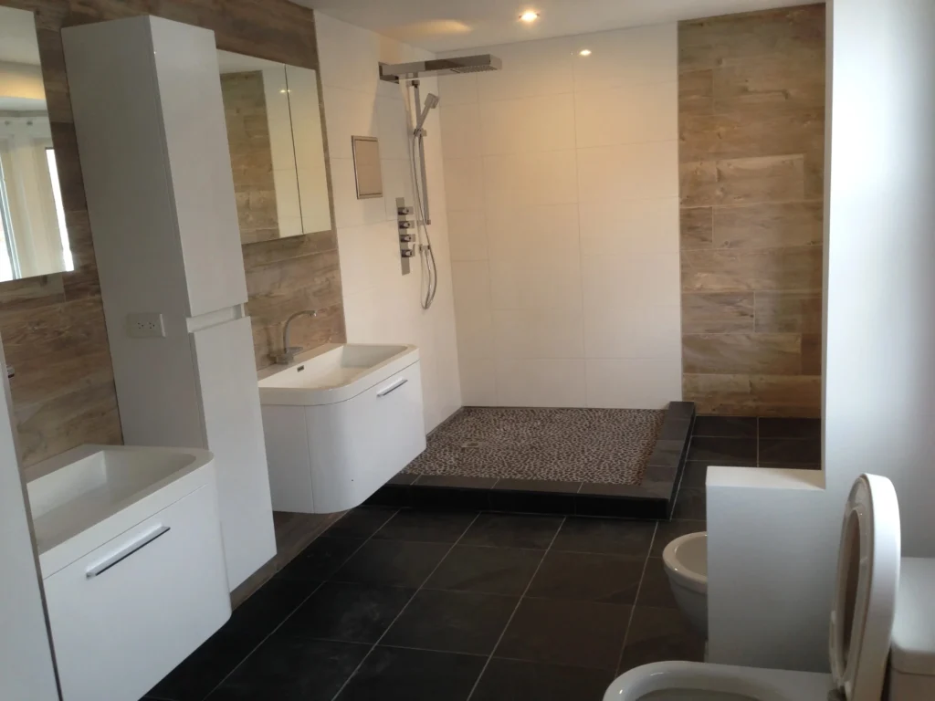 Raakss Reno bathroom renovation with two toilets, his and hers floating sinks, and a glass enclosed shower