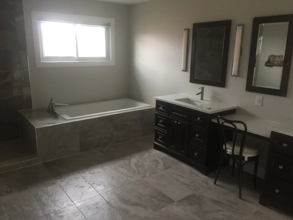 Raakss Reno bathroom renovation with his and her sinks, bath tub, and a powder area. Elegant wall sconces installed at eye level offer flattering, glare-free lighting ideal for grooming