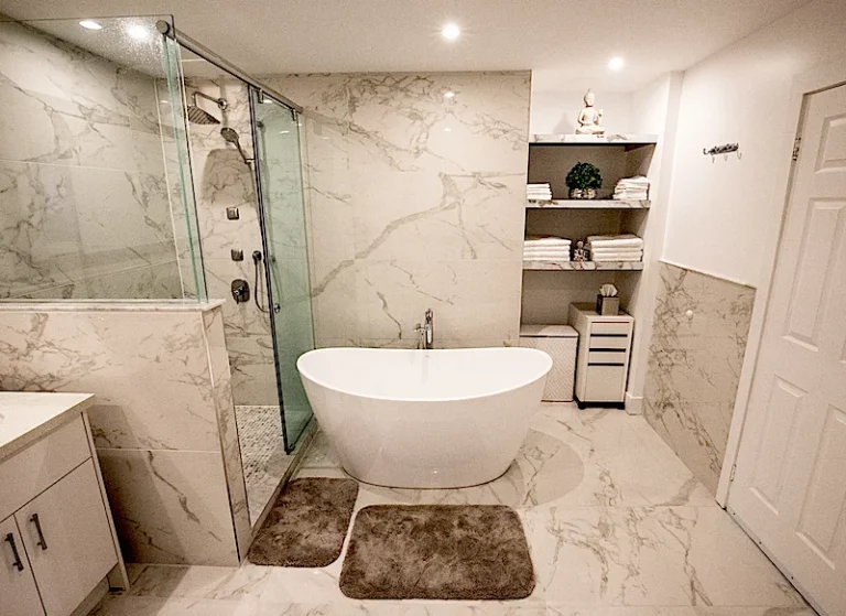 Raakss Reno Master bathroom renovation bath tub and glass enclosed shower with a storage area. Bathroom renovation budget tips