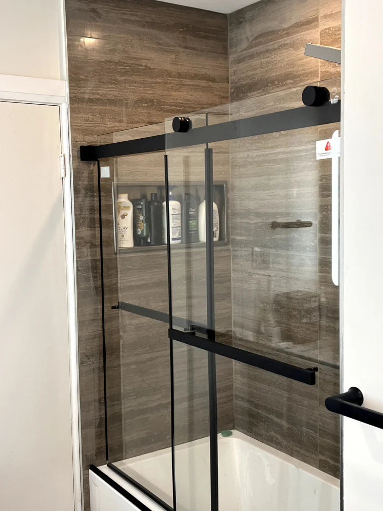 Glass shower door, tub, and niche behind the wall of the shower