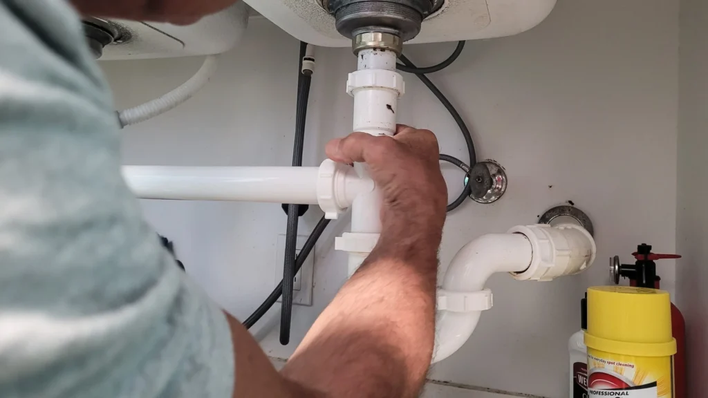 Plumber fixing a leaking bathroom sink pipe to stop mold growth